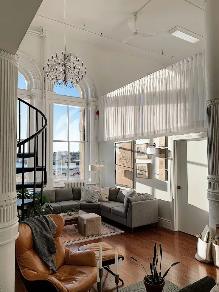 Light-filled loft living room with a spiral staircase and tall windows