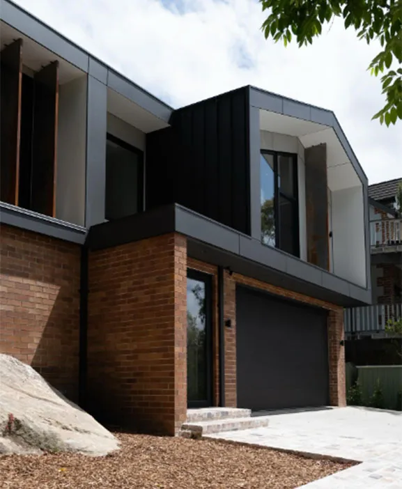 Two-storey modern home with black cladding and a brick base